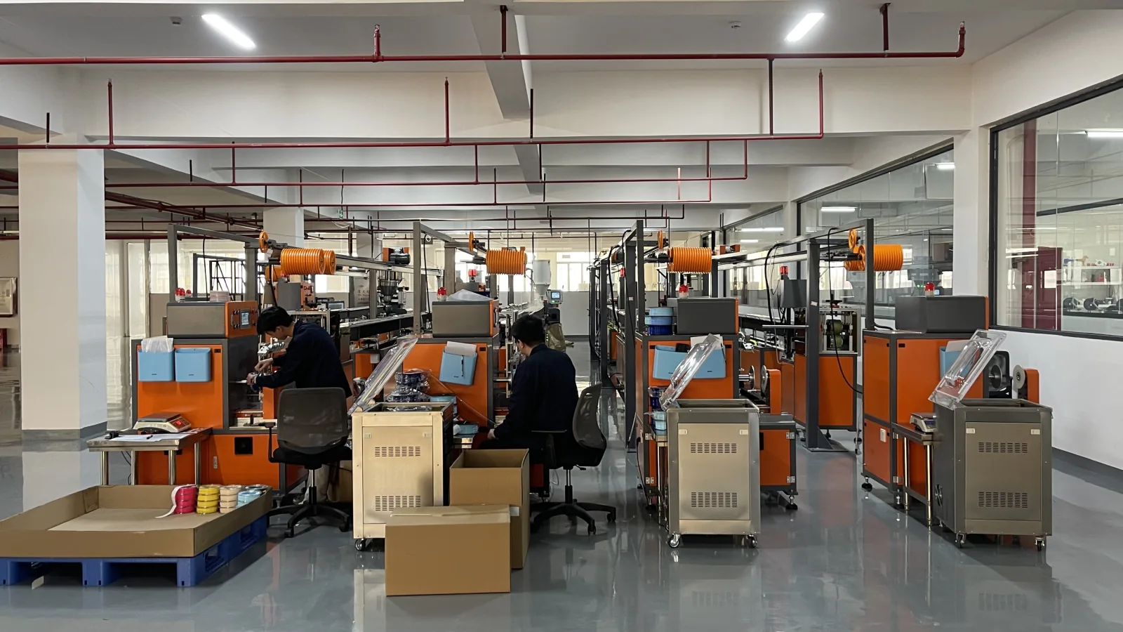 Vue d’ensemble de l’atelier de filament, avec équipements orange et gris, bobines et postes de travail
