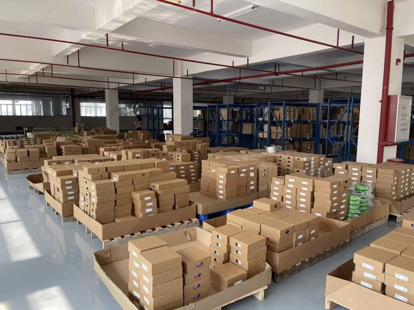 Palettes de cartons à côté de rayonnages bleus dans l’entrepôt